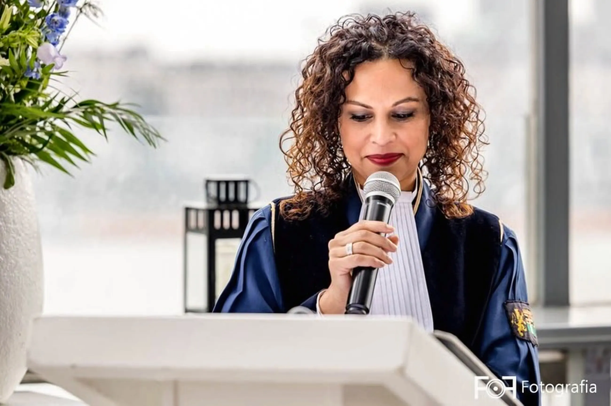 Angela spreekt met microfoon achter de lessenaar