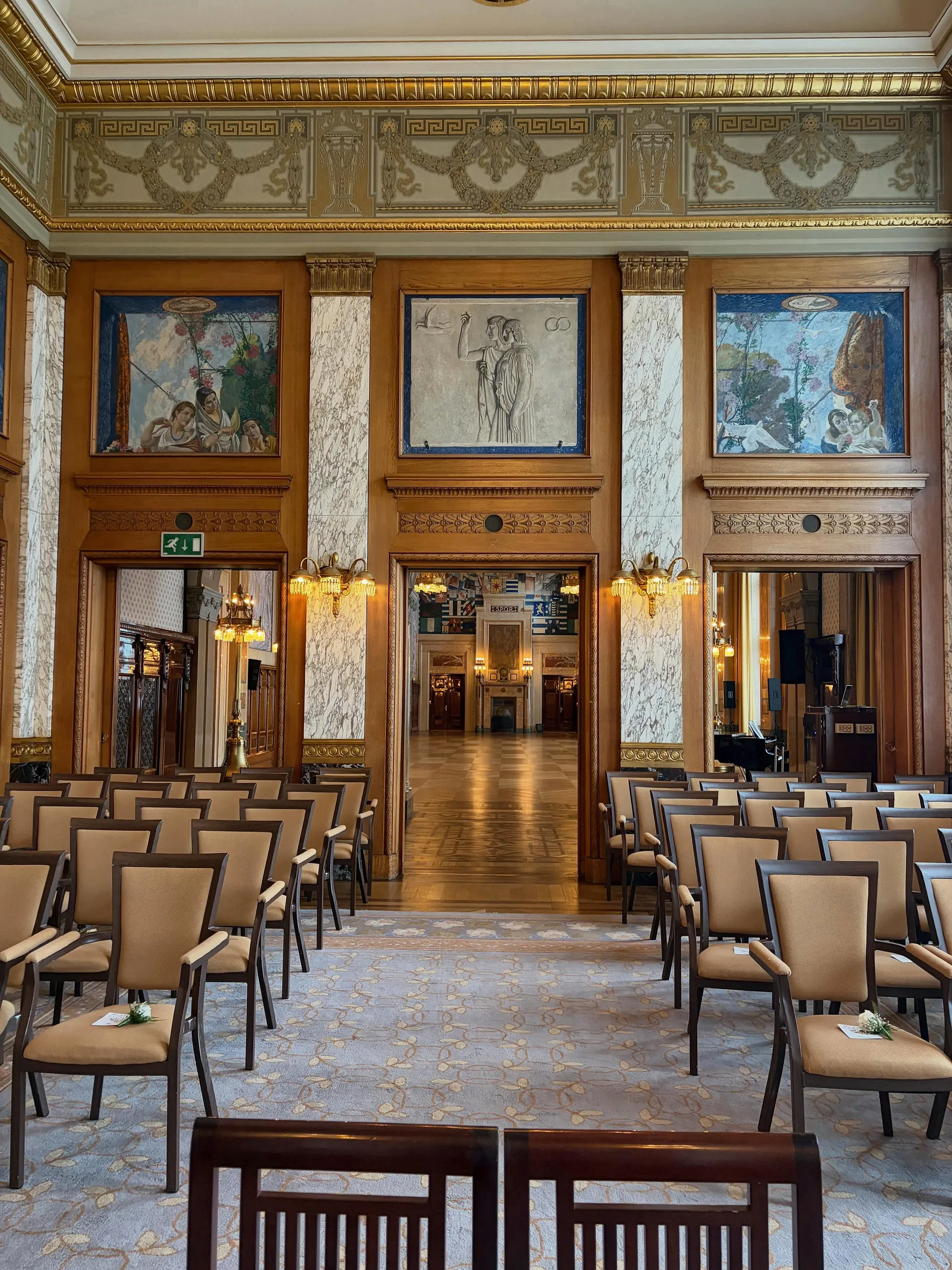 De Burgerzaal van het stadhuis van Rotterdam met rijen stoelen onder glas-in-lood