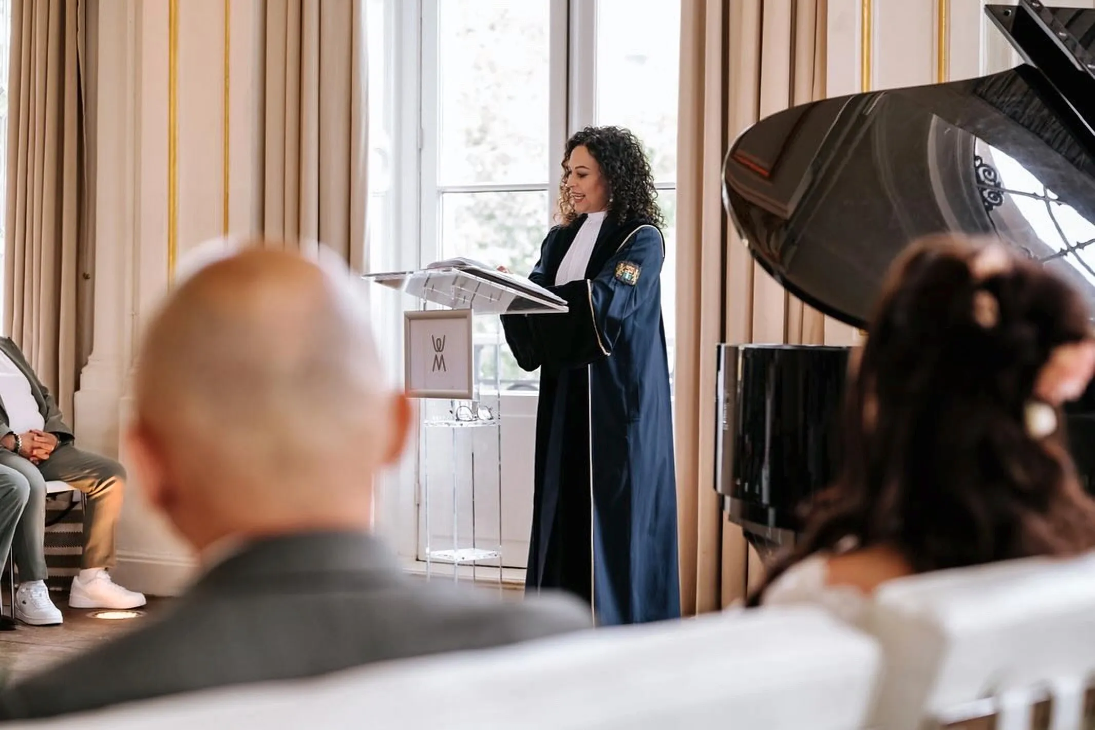 Angela houdt haar speech naast de vleugel, het bruidspaar op de voorgrond